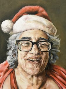 award of excellence: Janine by Justin Fitt's Features gray haired person with heavy black framed glasses in a Santa hat