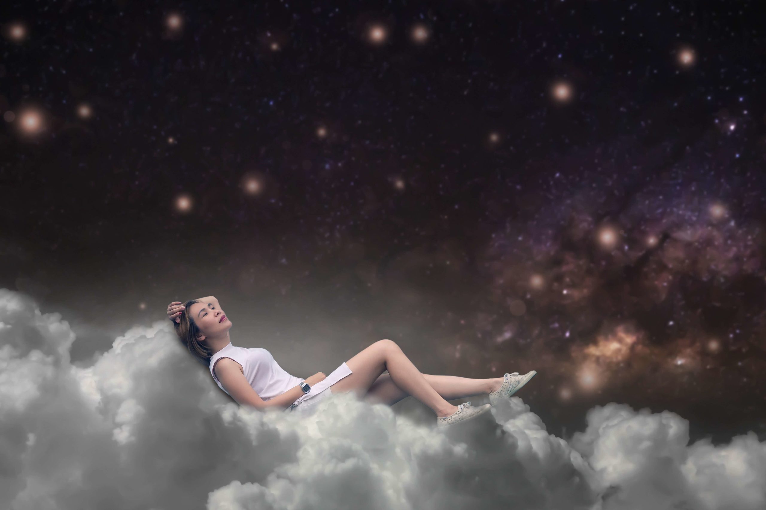 woman laying the white clouds looking up at a dark starry sky